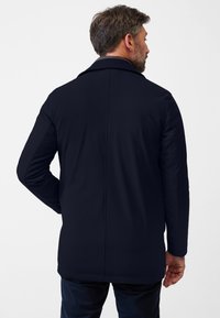 Marinkapp med skräddarsydd design, tillverkad av ett mjukt tyg. Har en urtagen krage och långa ärmar med en strukturerad passform.