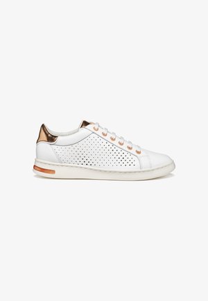Baskets basses blanches avec talon cuivre métallique, panneaux latéraux perforés, lacets blancs et semelle blanche avec accent cuivre près du talon.