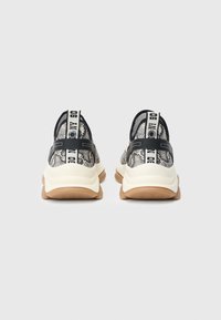 Αθλητικά παπούτσια με υφή από δίχτυ σε ασπρόμαυρο χρώμα στην επάνω πλευρά, με παχύ λευκού χρώματος πάτο και μαύρες ταμπελίτσες για να τα τραβάτε από τη φτέρνα με το λογότυπο.