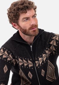 Schwarzer Reißverschluss-Pullover mit einer strukturierten Strickoptik, verziert mit geometrischen Mustern in Beige und Schwarz sowie einem gerippten Kragen.