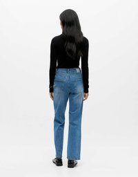 Plave traperice ravnog kroja, s pet džepova i izblijedelim pranjem. Nošene s crnim uskim dugim rukavima i crnim čizmama.