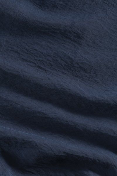 Dark navy fabric with a textured surface, featuring subtle wrinkles and a soft sheen. Material appears lightweight and smooth.