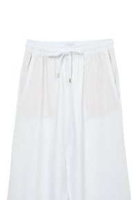 Pantalons en lin blancs avec une taille à cordon, dotés de poches latérales et d'un tissu doux à texture, avec une légère variation de couleur sur les côtés.