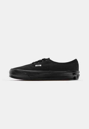 Schwarze Leinensneaker mit strukturiertem Obermaterial, Gummisohle und runder Zehenpartie. Mit schwarzen Schnürsenkeln und einem kleinen Logotag an der Seite.