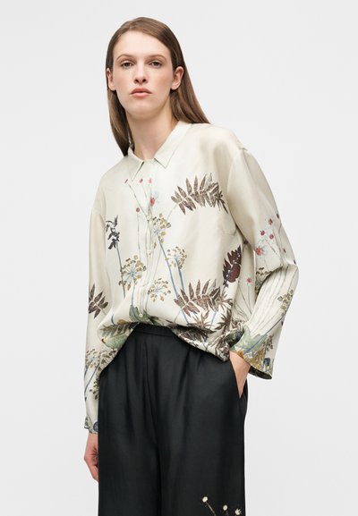 Ανοιχτόχρωμο, μεταξωτό μπλουζάκι με λουλουδένια σχέδια σε αποχρώσεις του πράσινου, καφέ και κόκκινου· γιακάς με κουμπιά· άνετη γραμμή με μακριά μανίκια.