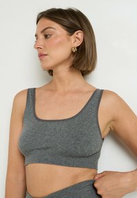 Bralette grigio a costine con scollatura rotonda, leggero rifinitura grigia e design senza cuciture, caratterizzato da una vestibilità confortevole.