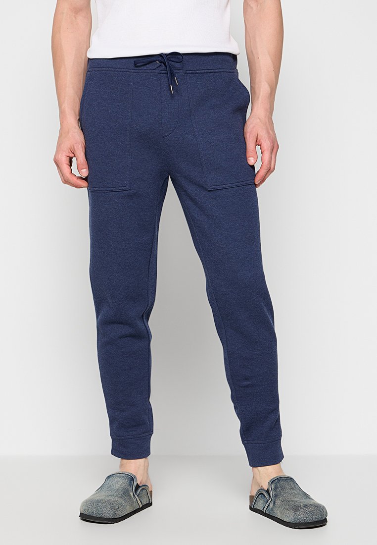 Granatowe dresowe spodnie z elastycznym pasem i sznurkiem, z dwiema przednimi kieszeniami i zwężającym się krojem nogawek. Miękka tekstura materiału.