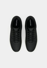 Μαύρα αθλητικά παπούτσια με λείο δερμάτινο επάνω μέρος, στρογγυλή μύτη, λευκή σόλα και μαύρα κορδόνια. Το εσωτερικό διαθέτει λογότυπο και διάτρητες λεπτομέρειες στα πλάγια.