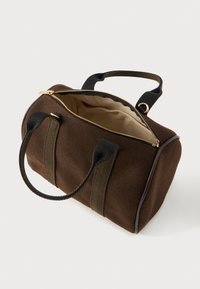 Μικρή σκούρα καφέ τσάντα υφάσματος με μαύρες λαβές, χρυσό φερμουάρ μερικώς ανοιχτό και μπεζ εσωτερική επένδυση, παρουσιασμένη σε γωνία πάνω σε λευκό φόντο.