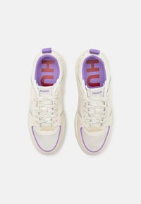Baskets de sport blanches et violettes avec des panneaux en mesh, des accents verts et un col rembourré. Elles affichent un logo rouge "HUGO" bien en vue sur la semelle intérieure.