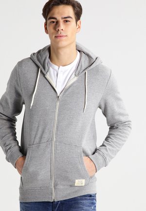 Grå zip-up hoodie med snøre, frontlommer og et lille mærke nederst til venstre. Blødt stof med en afslappet pasform og ribbede manchetter.