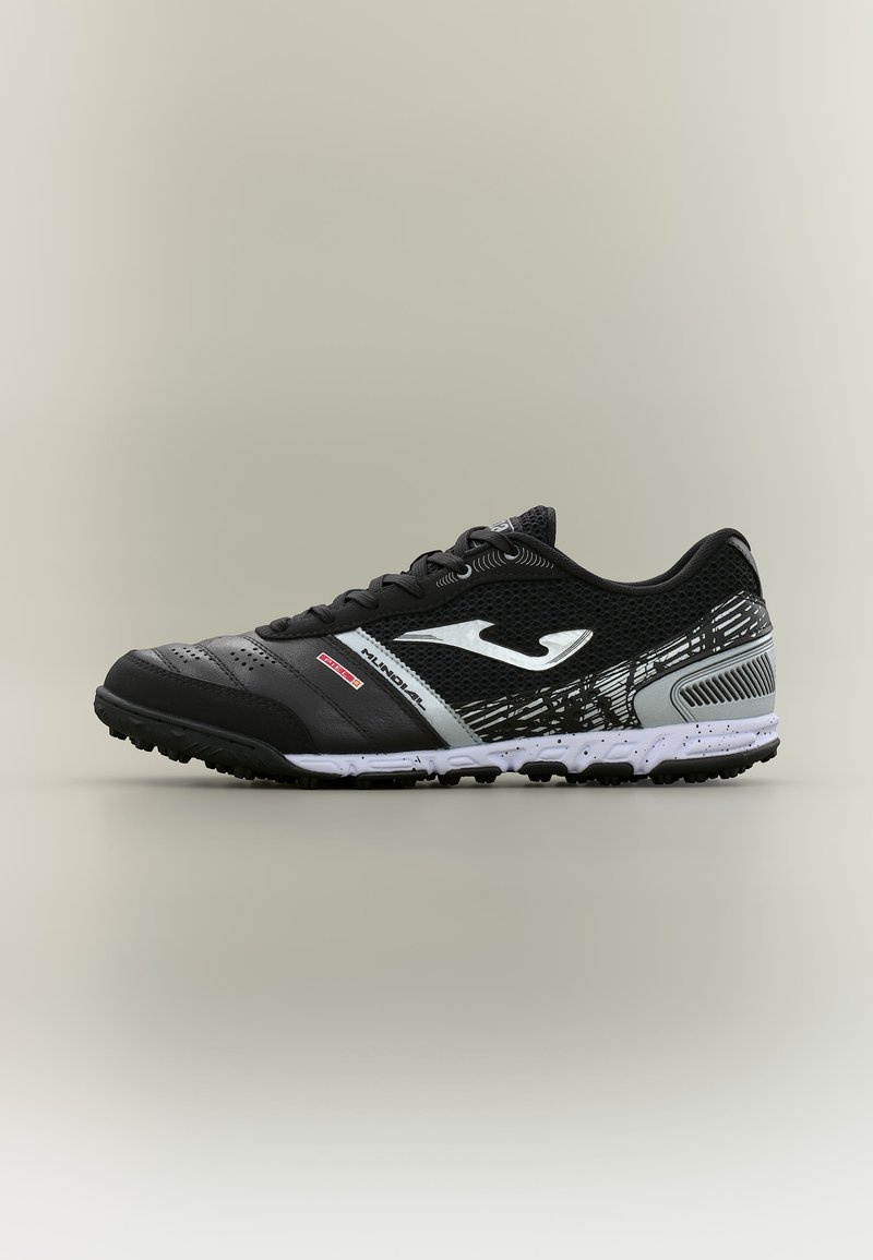 Αθλητικό παπούτσι σε μαύρο και γκρι με λευκό λογότυπο, υφασμένη σόλα και κορδόνια, σχεδιασμένο για χρήση σε τερέν γκαζόν ή εξωτερικούς χώρους.