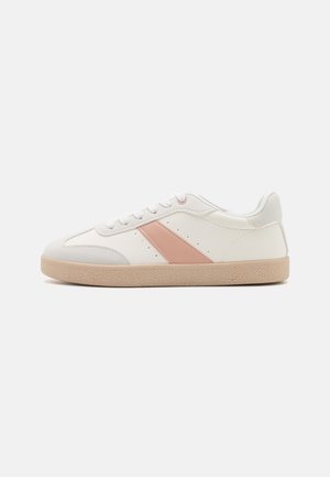 Witte lage sneaker met beige zool en een roze diagonale streep aan de zijkant, voorzien van witte veters en minimalistische perforatiedetails.