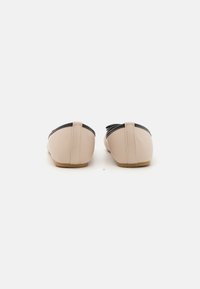 Balletskor i mjukt beige läder med en svart läderdetalj på toppen. Har rundad tå och en minimalistisk design.