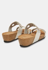 Sandali bianchi con sole in sughero, dotati di cinturini texturizzati decorati con perline e dettagli intagliati. Suola in gomma per aderenza.