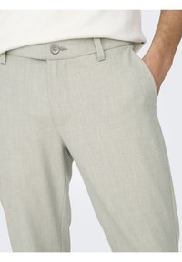Pantalones de vestir gris claro con una textura sutil, con cierre de botón, bolsillos laterales y un corte ajustado.