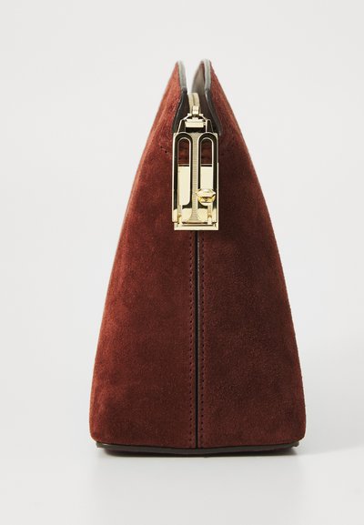 Κόκκινη σουέτ τσάντα χειρός σε τριγωνικό σχήμα, με χρυσό κούμπωμα και μαύρη επένδυση στην κορυφή. Επιφάνεια με υφή, χωρίς ορατά σχέδια.