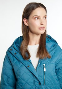 Teal quiltet jakke med hætte, der har en lynlåslomme og trykknaplukninger. Glat tekstur med et diamantmønstret design.