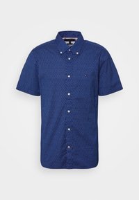 Blaues Hemd mit kurzen Ärmeln und Knöpfen, mit einem weißen abstrakten Muster, aus Stoff mit glatter Struktur. Verfügt über eine Tasche und einen Kragen.