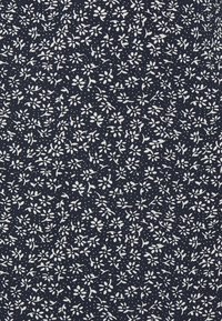 Marinestoff mit einem kleinen floralen Muster in Weiß, mit Blumenclustern, Blättern und Punkten, die ein strukturiertes Erscheinungsbild erzeugen.
