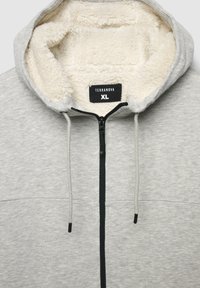 Felpa con zip grigia chiara con rivestimento in pile bianco all'interno del cappuccio, zip nera, coulisse e etichetta di taglia XL all'interno del colletto.