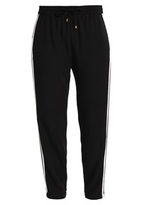 Pantalon de jogging noir avec taille à cordon, jambes fuselées et bandes blanches sur les côtés. Confectionné dans un matériau doux avec une texture minimale.