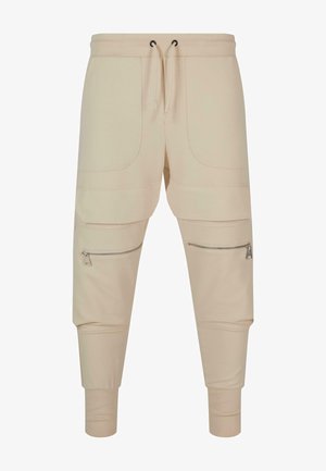 Beige sporta bikses ar auklu vidukļa, divām priekšējām kabatām, ar rāvējslēdzējiem sānu kabatām, ribotām aprocēm un gludu kokvilnas auduma tekstūru.