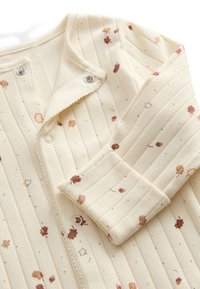 Cremefarvet ribbet onepiece med små blomsterprint i brun og orange. Har trykknapper og tekstureret stof for komfort.