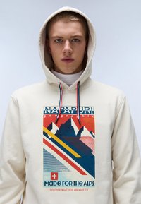 Biała bluza z kapturem z graficznym nadrukiem przedstawiającym górski wzór w odcieniach czerwieni, niebieskiego, żółtego i kremowego. Zawiera sznurki do ściągania z akcentami w kolorze czerwonym i niebieskim.