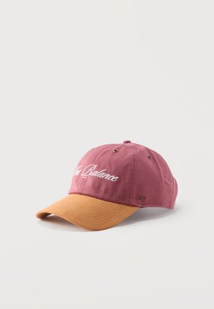 Καπέλο μπέιζμπολ με κορόνα σε αχνό ροζ και κυρτή γείσο σε κίτρινο μουστάρδας, με λευκή, καλλιγραφική κεντητή επιγραφή "New Balance" μπροστά.