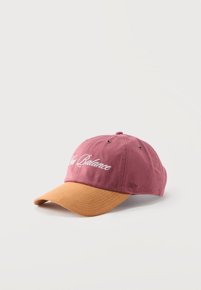 Καπέλο μπέιζμπολ με κορόνα σε αχνό ροζ και κυρτή γείσο σε κίτρινο μουστάρδας, με λευκή, καλλιγραφική κεντητή επιγραφή "New Balance" μπροστά.