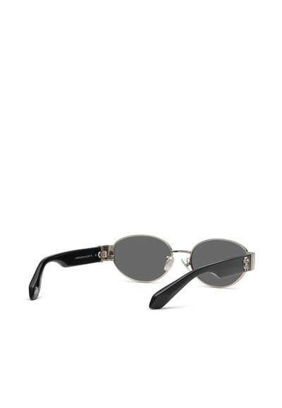 Lunettes de soleil ovales avec des verres sombres, une fine monture métallique et des branches noires courbées reposant sur une surface blanche.