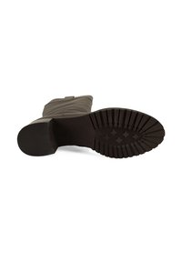 Botte marron avec une semelle en caoutchouc texturé, présentant un motif strié pour une meilleure adhérence et un matériau supérieur doux et lisse. Talon plat pour la stabilité.