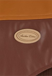 Braune Kunstledertasche mit glatter Oberfläche, einem hellbraunen Lederklappen und einem gestickten ovalen Etikett mit dem Aufdruck "Another Cotton".