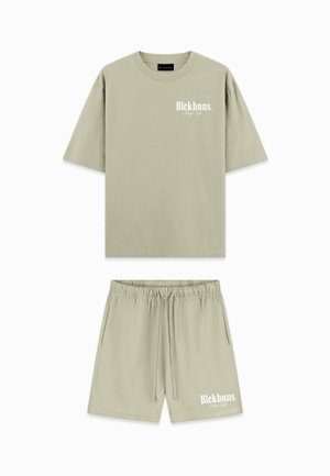 Light olive green cotton short-sleeve t-shirt and matching shorts. Features white logo text on both items. Elastic waistband on shorts.