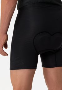 Pantaloni corti neri realizzati in tessuto elasticizzato, con un'imbottitura a forma di cuore sul retro, con una texture liscia e un design senza cuciture.