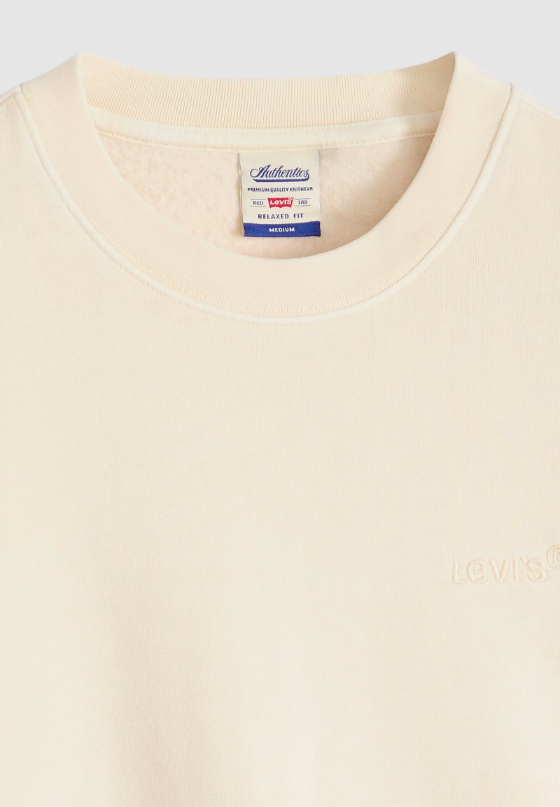 Felpa color crema con scollo rotondo, logo Levi's ricamato sul petto e etichetta che indica una vestibilità comoda, taglia media.