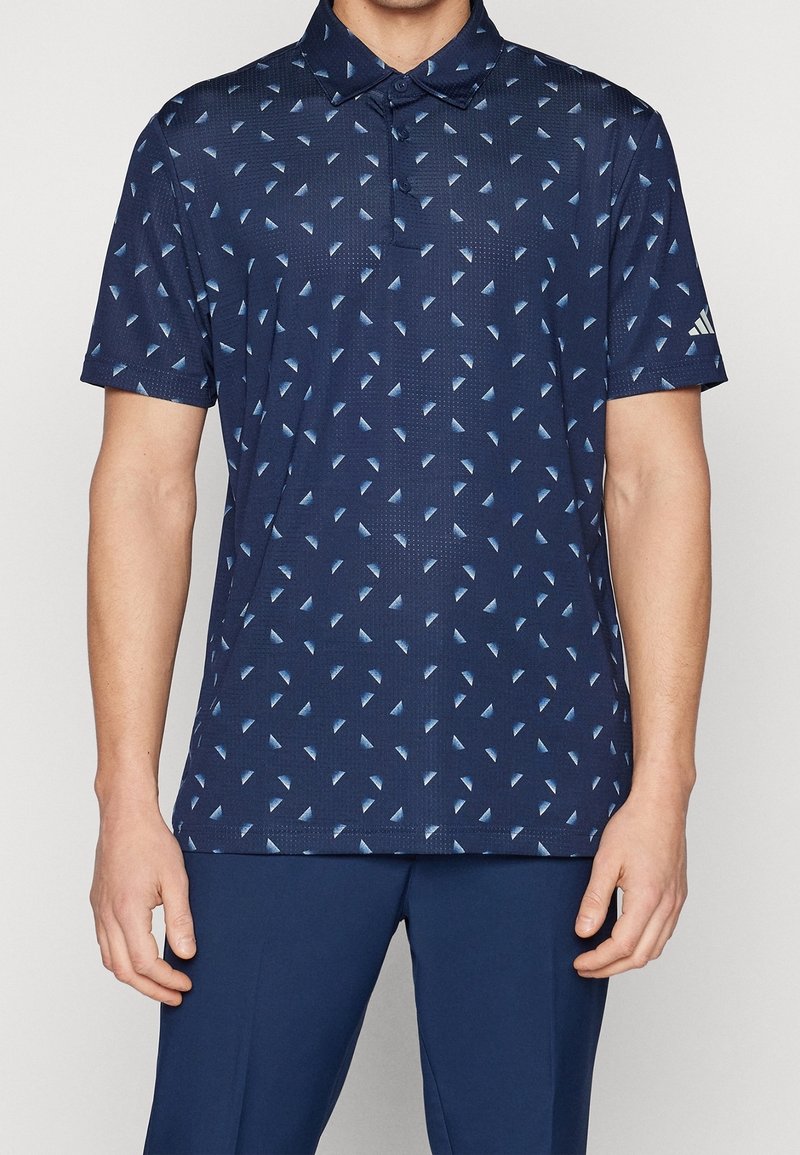 Tmavě modrá polokošile s geometrickým světle modrým vzorem, krátkými rukávy a límečkem. Vyrobena z texturované látky. Logo značky na rukávu.