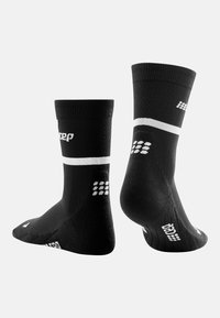 Schwarze Sportsocken mit einem gerippten Design, weißen Akzenten und Logo. Sie verfügen über eine verstärkte Ferse und Zehenkappe für Haltbarkeit und Unterstützung.