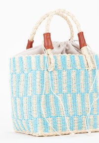 Vävd korgväska med ett randigt mönster i ljusblå och naturliga toner, med flätade handtag inlindade i brunt läder och ett tygfoder.