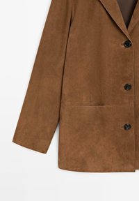 Bruine suède jas met lange mouwen en drie zwarte knopen aan de voorkant, weergegeven tegen een witte achtergrond.