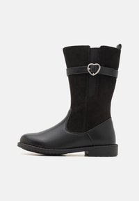 Botte noire mi-mollet en cuir et daim mélangés, ornée d'une sangle décorative avec boucle argentée en forme de cœur et d'un petit talon bloc.