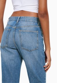 Jeans in denim blu chiaro con vita alta, dotati di due tasche posteriori e cuciture a contrasto. Il tessuto appare leggermente vissuto.