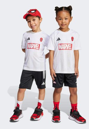 Bílé dresy značky Marvel s červeným logem Spider-Mana, černé šortky s bílými pruhy, červená kšiltovka Spider-Man a odpovídající červené a černé sportovní boty.