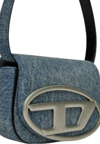 Borsa a tracolla in denim con logo in metallo argentato arrotondato e tracolla nera. Tessuto blu texture con chiusura a pattina.