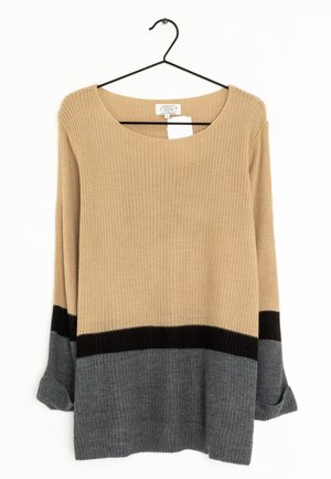 Beżowy, czarny i szary sweter w kolorowe bloki z dzianiny z długimi rękawami, wiszący na czarnym wieszaku na białym tle.