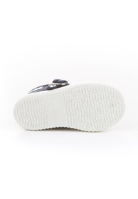 Suela de zapato hecha de goma blanca texturizada, con un patrón de surcos en relieve y "HECHO EN ESPAÑA" grabado en el lateral.