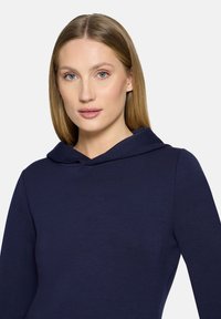 Granatowa bluza z kapturem o gładkiej teksturze i dopasowanym kroju, z bliskim dekoltem oraz długimi rękawami.