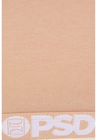 Lys beige ribbet stoff med en elastisk midjebånd som har hvit "PSD" merkevare. Jevn tekstur, tettsittende design og jevn farge.