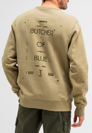Beige sweatshirt met groene graphics op de achterkant, met de tekst "BUTCHER OF BLUE." Zacht materiaal, geribde manchetten en zoom.